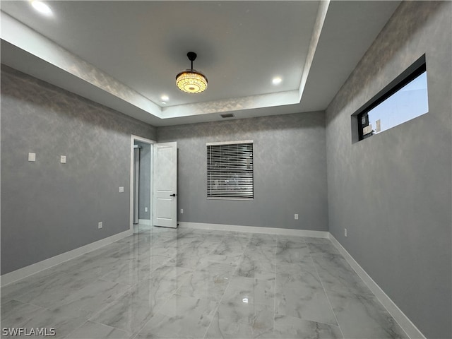 spare room featuring light tile flooring and a raised ceiling