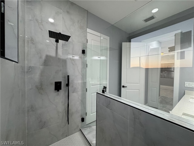 bathroom featuring a shower with shower door and vanity