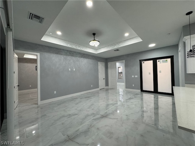 unfurnished room with a tray ceiling, light tile flooring, and elevator