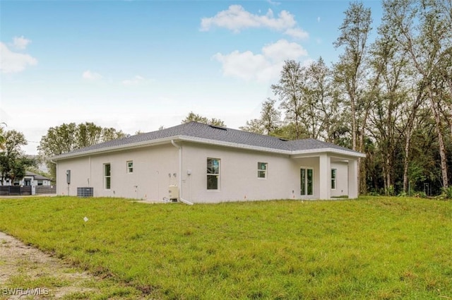 rear view of house with central AC and a yard