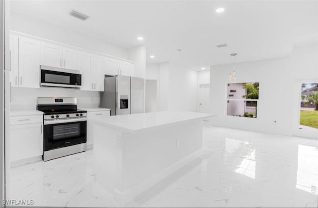 kitchen with white cabinetry, stainless steel appliances, decorative light fixtures, and a kitchen island