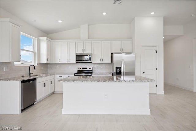 kitchen with white cabinets, appliances with stainless steel finishes, sink, and a kitchen island