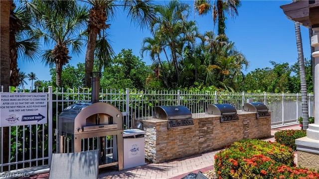 view of patio with an outdoor kitchen, fence, and a grill