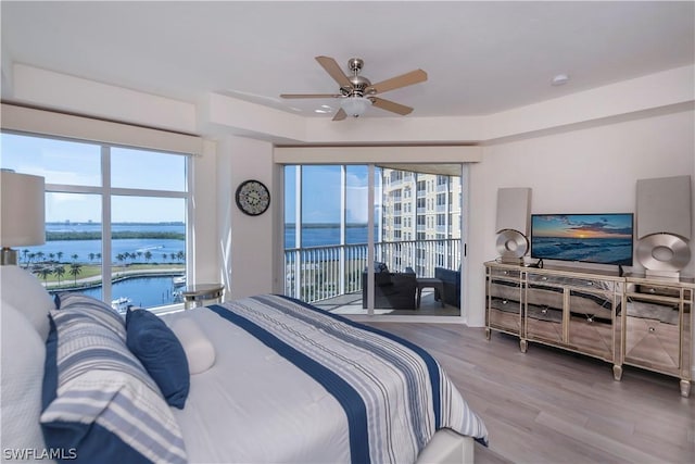 bedroom with a water view, ceiling fan, and wood-type flooring