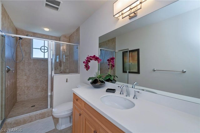 bathroom with vanity, toilet, visible vents, and a stall shower