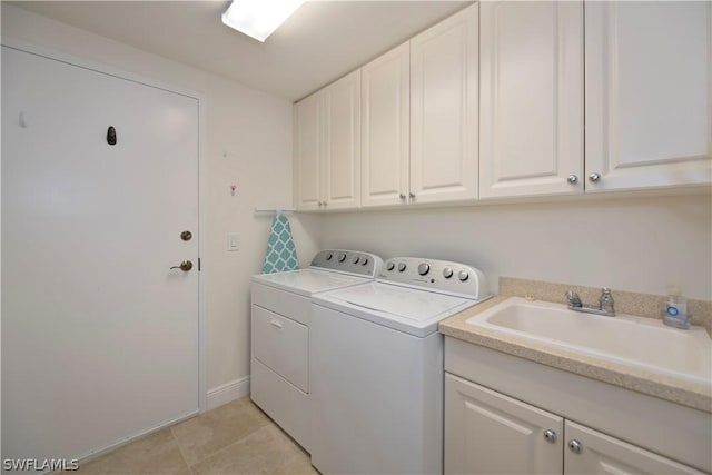 clothes washing area featuring light tile patterned flooring, cabinets, separate washer and dryer, and sink