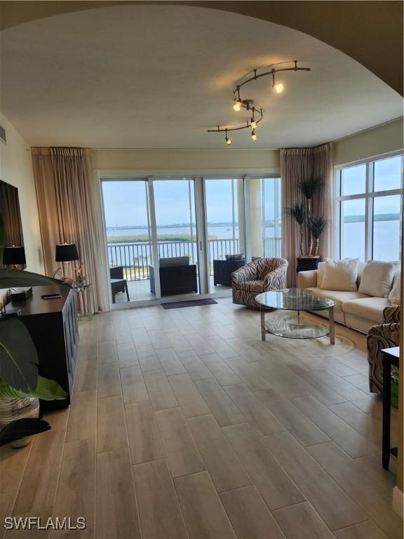 living room with a water view, plenty of natural light, and light wood-type flooring