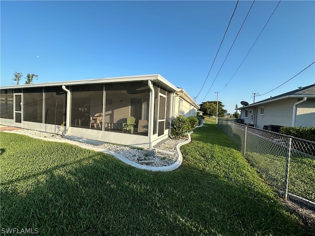 back of property featuring a sunroom and a lawn