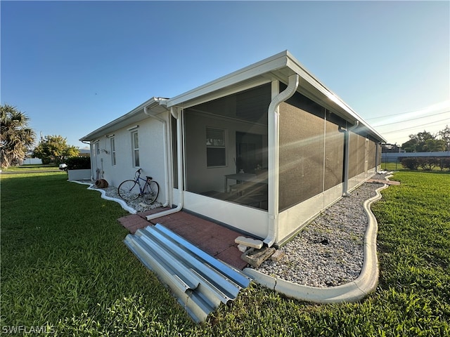 view of side of property with a sunroom and a lawn