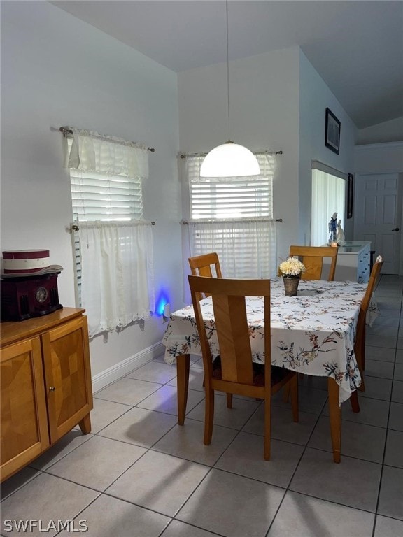 dining room with light tile floors and vaulted ceiling