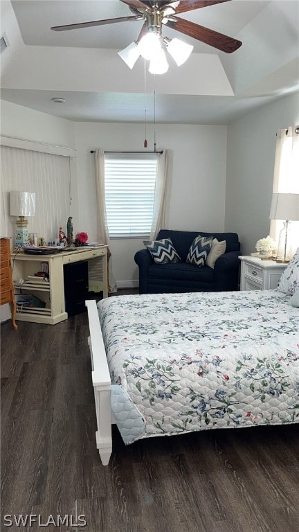 bedroom with ceiling fan, multiple windows, a raised ceiling, and dark hardwood / wood-style flooring