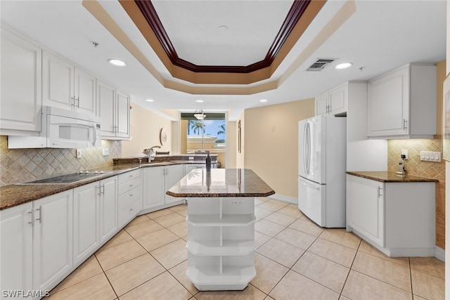 kitchen with a kitchen island, tasteful backsplash, crown molding, white appliances, and white cabinets