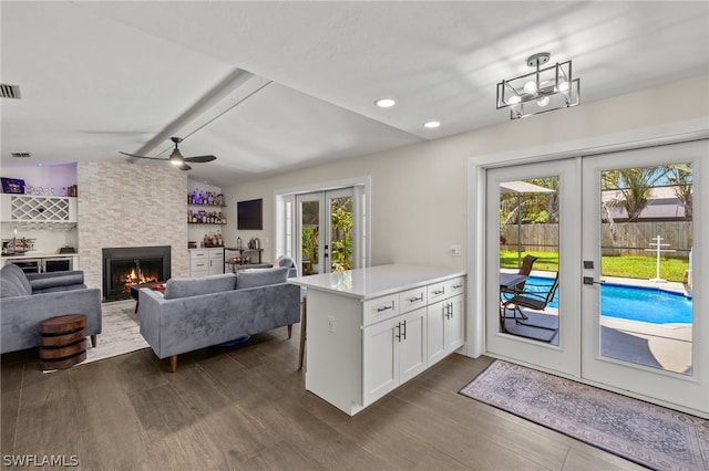 kitchen featuring dark wood-style flooring, a fireplace, white cabinets, light countertops, and french doors