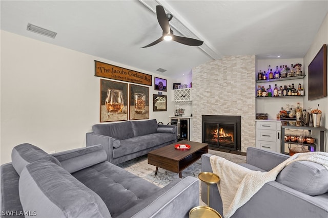 living room featuring vaulted ceiling with beams, visible vents, a fireplace, and a bar