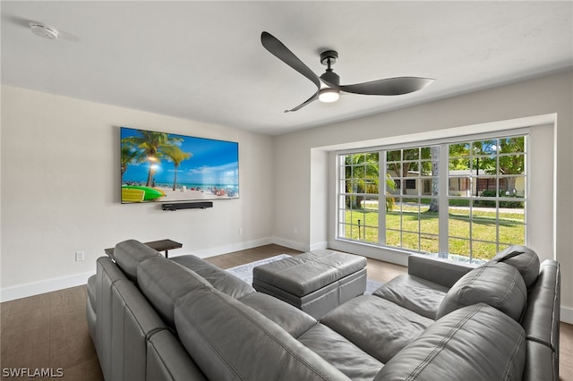 living room with a ceiling fan, baseboards, and wood finished floors