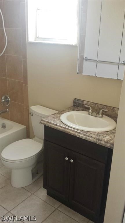 full bathroom featuring toilet, vanity, tile patterned floors, and tiled shower / bath