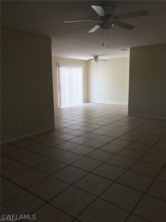 tiled spare room featuring ceiling fan