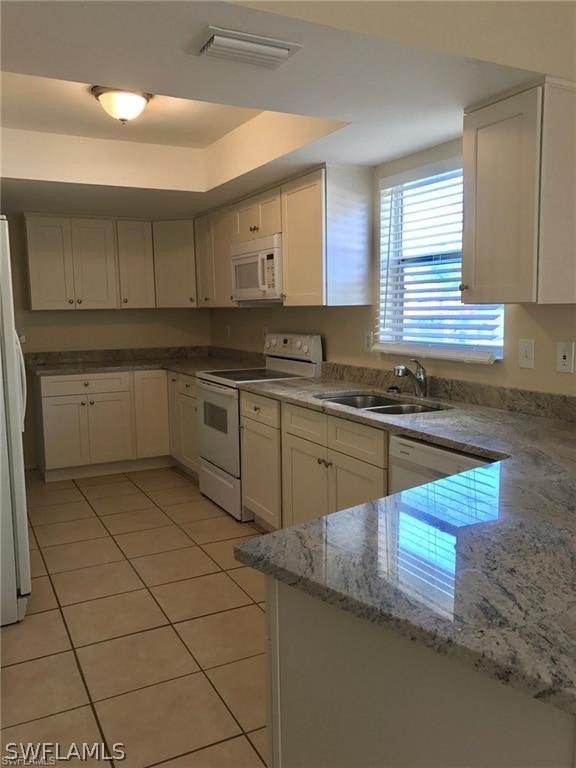 kitchen featuring white cabinets, light tile patterned floors, white appliances, and sink