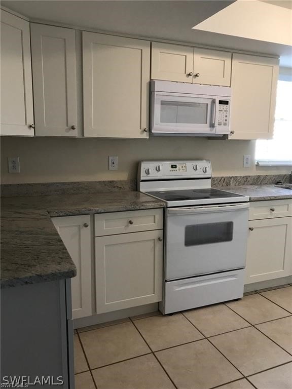 kitchen with white cabinets, white appliances, and light tile patterned floors