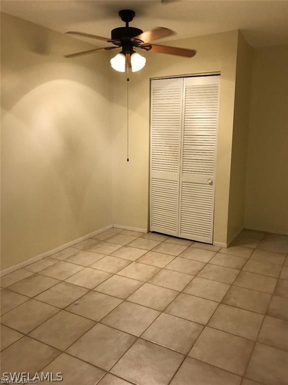 unfurnished bedroom featuring ceiling fan, light tile patterned floors, and a closet