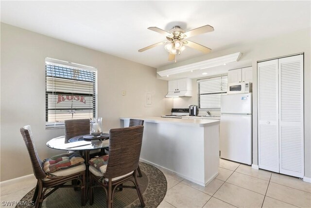 kitchen featuring white appliances, white cabinets, sink, light tile patterned floors, and kitchen peninsula