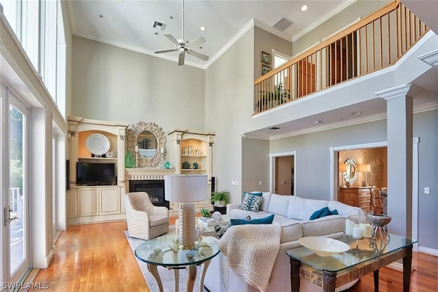 living room featuring a towering ceiling, light hardwood / wood-style floors, and ornamental molding