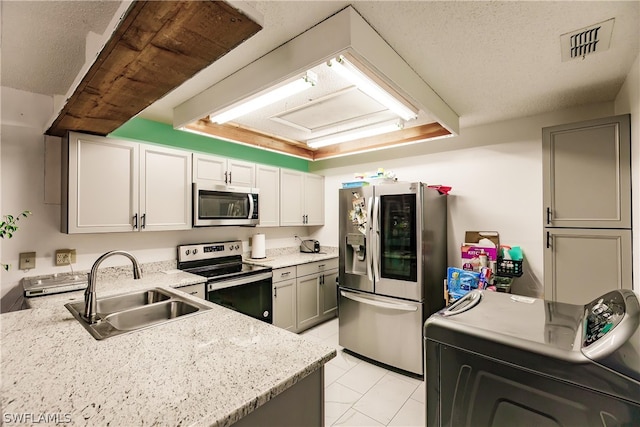 kitchen with washer / dryer, visible vents, appliances with stainless steel finishes, gray cabinetry, and a sink