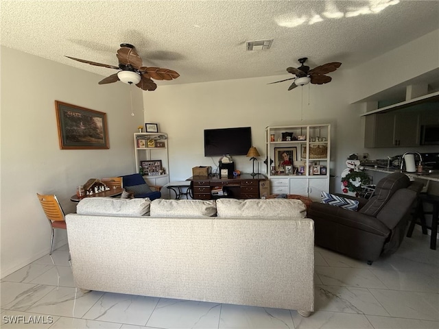 living room with a textured ceiling, marble finish floor, visible vents, and a ceiling fan