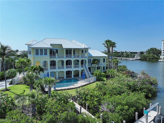 back of house featuring a balcony, a patio area, and a water view