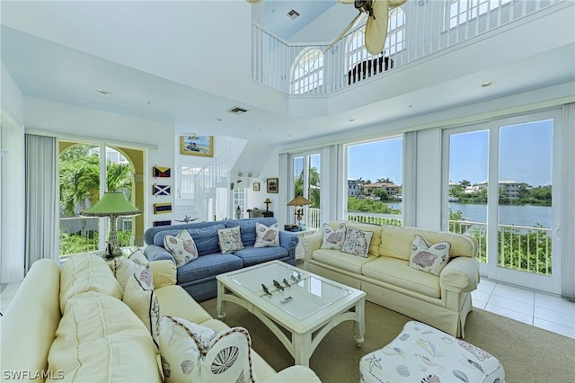 tiled living room with a high ceiling and a water view