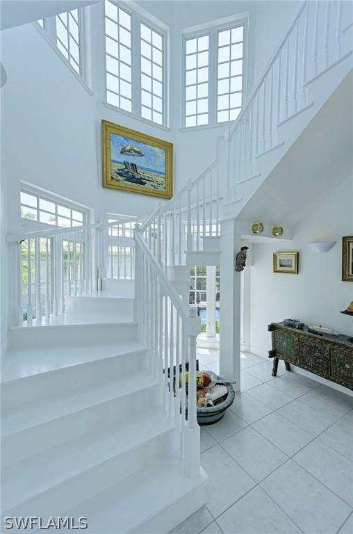 stairs with a towering ceiling, tile flooring, and plenty of natural light