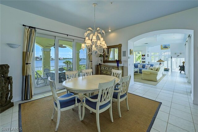 dining space with light tile flooring, a water view, and an inviting chandelier