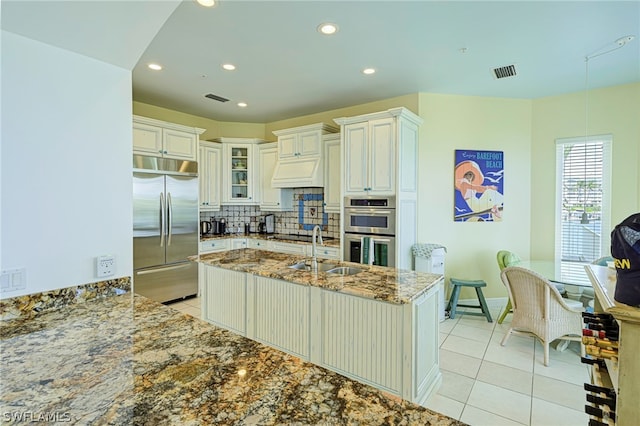 kitchen with appliances with stainless steel finishes, sink, tasteful backsplash, and light tile floors