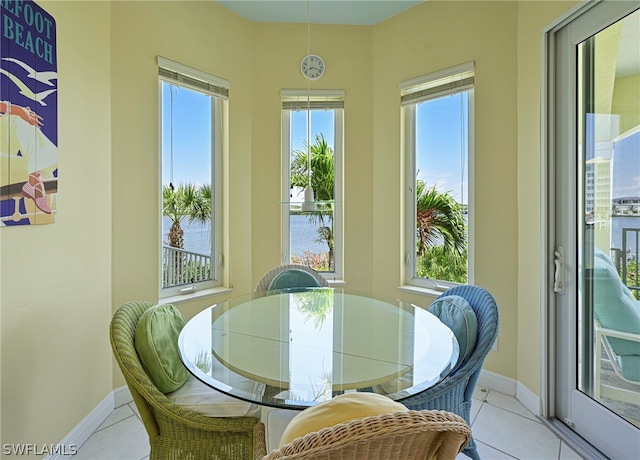 tiled dining space featuring a healthy amount of sunlight and a water view