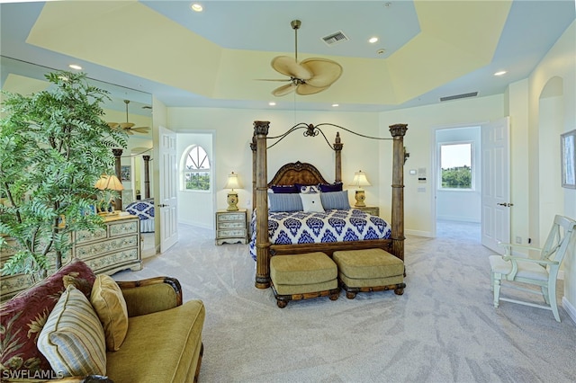 carpeted bedroom with ceiling fan and a tray ceiling