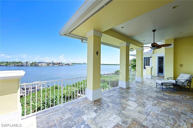 view of patio with a water view and ceiling fan