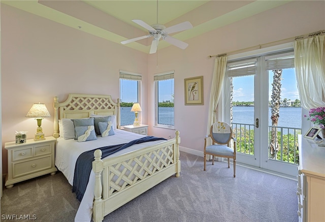 bedroom with dark carpet, ceiling fan, a water view, and access to outside