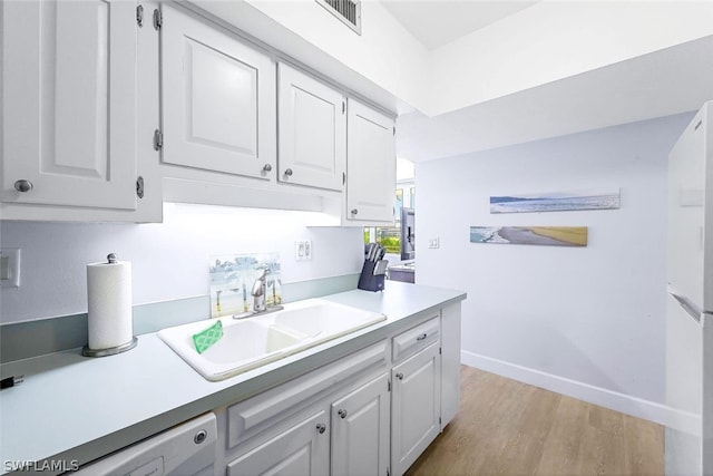 kitchen with sink, white cabinets, light wood-type flooring, and white dishwasher