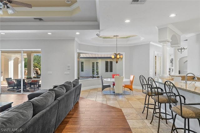 15401 Old Wedgewood Ct, Fort Myers, FL 33908 - living room featuring ornate columns, ceiling fan with notable chandelier, sink, ornamental molding, and a tray ceiling