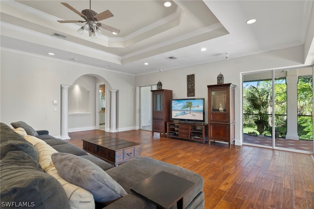 living room featuring ceiling fan, a raised ceiling, crown molding, and wood-type flooring