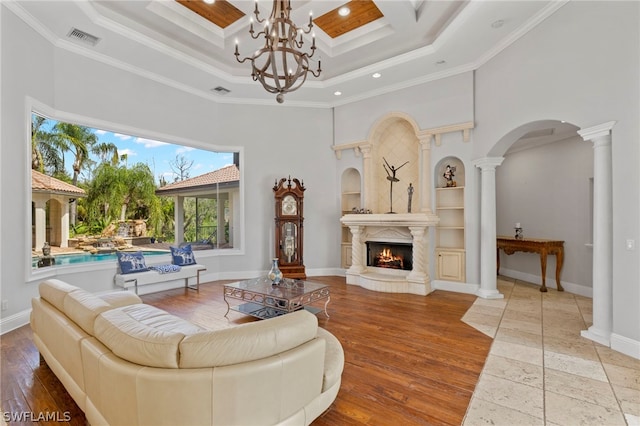 living room with a notable chandelier, ornamental molding, a tray ceiling, and coffered ceiling