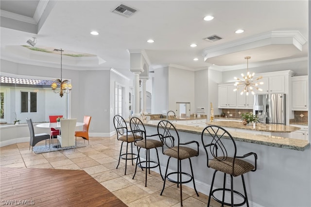 kitchen featuring white cabinetry, hanging light fixtures, crown molding, stainless steel fridge, and light tile floors