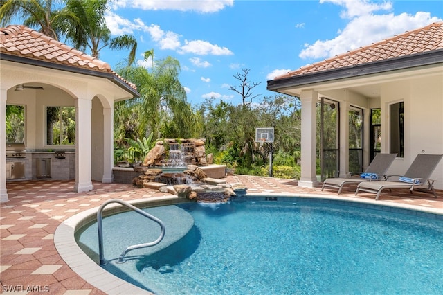 view of pool featuring a fireplace, a patio area, and area for grilling