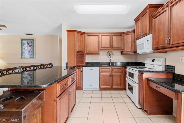 kitchen featuring dark stone countertops, sink, white appliances, and light tile floors