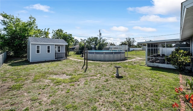 view of yard with an outdoor structure, a sunroom, and a fenced in pool