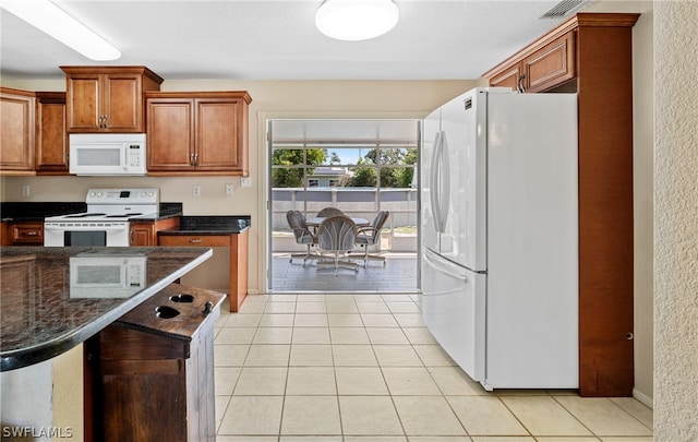 kitchen featuring white appliances, dark stone counters, and light tile flooring