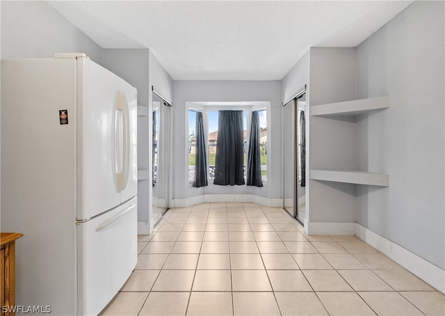 kitchen featuring a textured ceiling, white fridge, and light tile floors