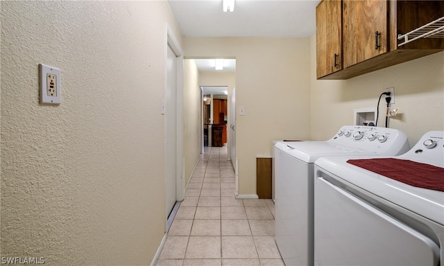 washroom featuring washing machine and clothes dryer, washer hookup, light tile flooring, and cabinets