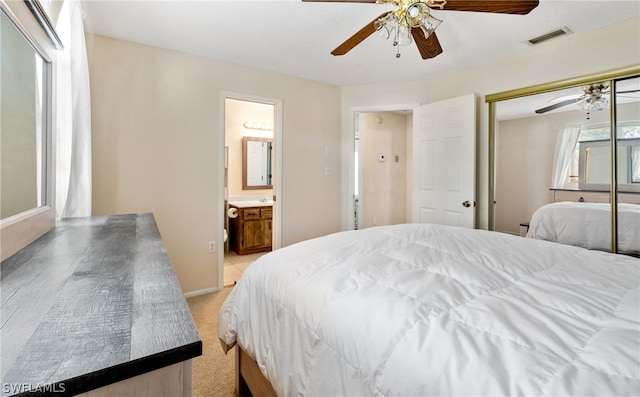 bedroom featuring ceiling fan, a closet, light carpet, and ensuite bathroom