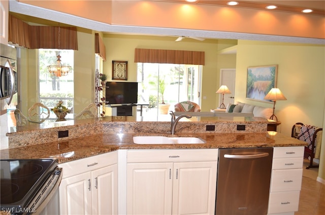 kitchen featuring dark stone counters, stainless steel appliances, tile floors, sink, and white cabinets